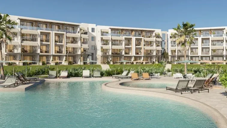 Außenansicht eines modernen Resorts mit vierstöckigen Gebäuden, Balkonen, Palmen und einem geschwungenen Swimmingpool, umgeben von Liegestühlen und viel Grün – ideal zum Entspannen nach einer Golfrundreise durch Irland – unter strahlend blauem Himmel.