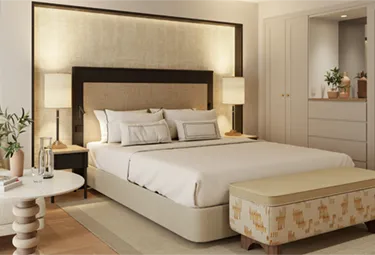 Ein modernes, in neutralen Farbtönen gehaltenes Schlafzimmer im Melia Hacienda del Conde verfügt über ein großes Bett mit weißer Bettwäsche, zwei Nachttische mit Lampen, eine gepolsterte Bank am Fußende des Bettes, Einbauschränke, kleine Pflanzen und eine durchgehend minimalistische Einrichtung.