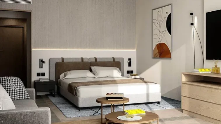 Ein modernes Schlafzimmer mit einem Doppelbett, neutraler Bettwäsche, zwei Nachttischen, abstrakter Wandkunst, die an eine Golfrundreise durch Irland erinnert, einem an der Wand montierten Fernseher, einer Kommode, einem Sofa und einem runden Couchtisch mit Büchern – alles in sanften, gedeckten Farbtönen.